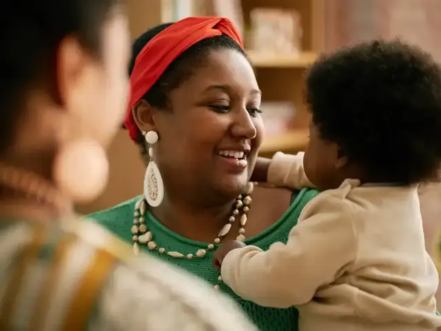 Smiling mother holding her baby while chatting with family