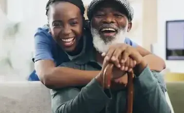 Caregiver hugging an elderly man at home