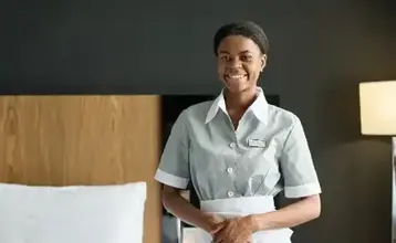 Chambermaid wearing uniform standing in a hotel room