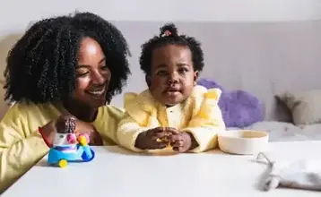 Nanny sitting at a table with a baby